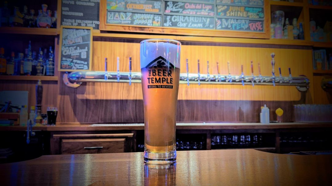 a tall glass of foamy beer on the bar at The Beer Temple in Chicago